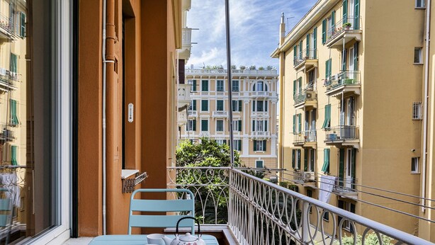 A balcony with a table and chairs, a view of adjacent buildings, and a railing. - Light Apartment in Albaro (Genoa)