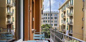 A balcony with a table and chairs, a view of adjacent buildings, and a railing. - Light Apartment in Albaro (Genoa)