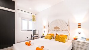 Une chambre d’hôtel avec un grand lit, une table de chevet avec une lampe, une chaise et une fenêtre avec des rideaux.