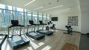 Een moderne sportschool met loopbanden, spinningfietsen en een motiverende quote op de muur.
