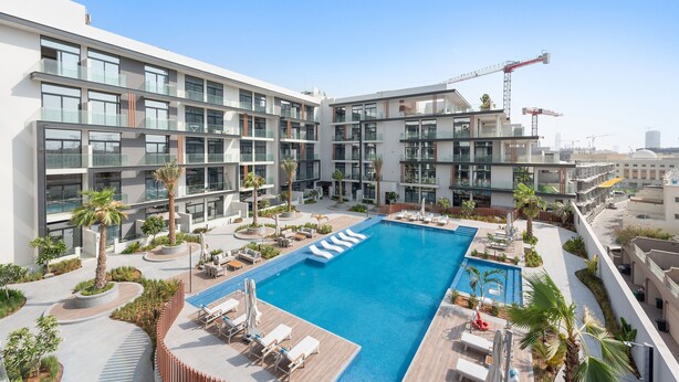 A modern hotel with a rooftop pool, multiple balconies, and a landscaped garden area. - Oxford 212 - 303 2BD (Dubai)