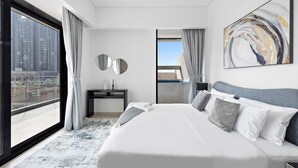 A modern hotel room with a large bed, a desk, and a view of the cityscape through floor-to-ceiling windows. - Oxford 212 - 303 2BD (Dubai)