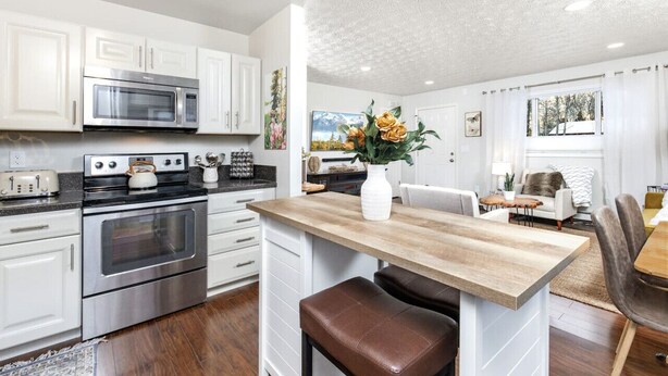 A modern kitchen with white cabinets, stainless steel appliances, and a wooden island with seating.