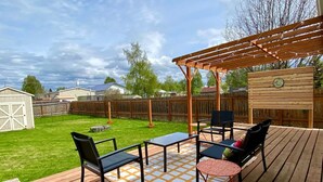 An outdoor deck with a pergola, a table with chairs, and a small round table with a chair.