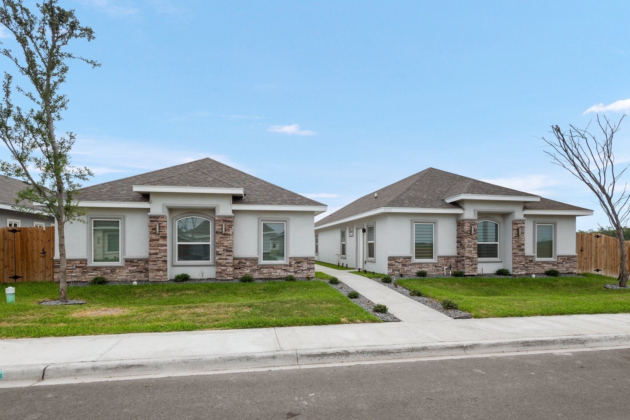 Un quartier résidentiel comprenant deux maisons modernes, caractérisées par des éléments en pierre et des toits à deux versants.
