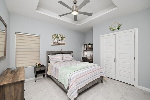 A bedroom with a bed, a nightstand, a dresser, a ceiling fan, and a white door. - Peaceful & Cozy Hideaway Unit #2 (Edinburg)