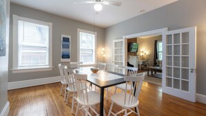 Un espace repas avec une table ronde, des chaises blanches et un ventilateur de plafond.