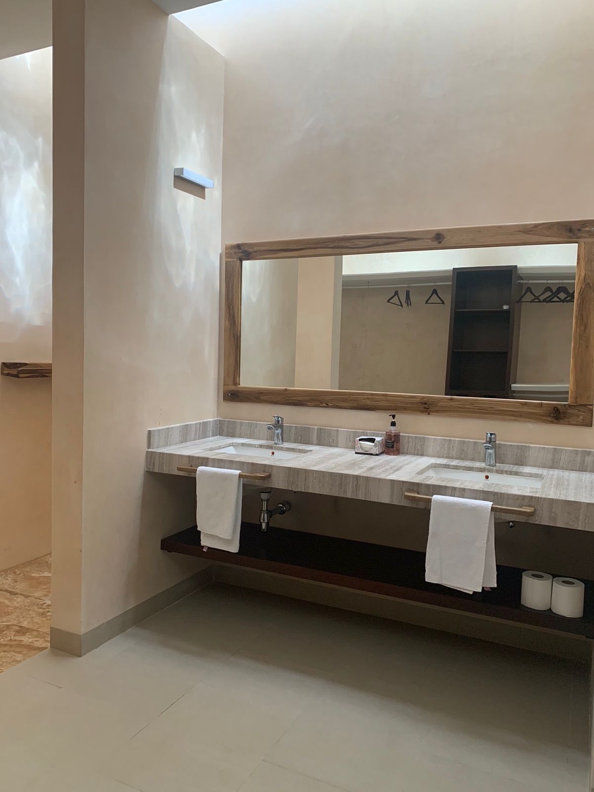Un baño con dos lavamanos, un espejo grande y un perchero para toallas.