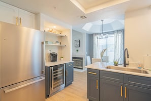 Una cocina moderna con refrigerador de acero inoxidable, horno empotrado y armarios oscuros con detalles dorados.