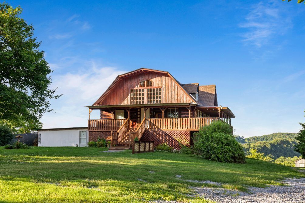 A large wooden house with a porch, a staircase, and a garage.