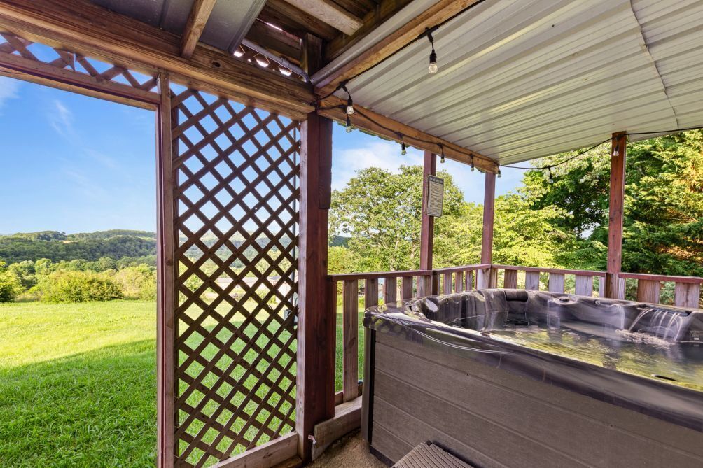 Un bain à remous sous une pergola en bois, avec vue sur un paysage verdoyant.