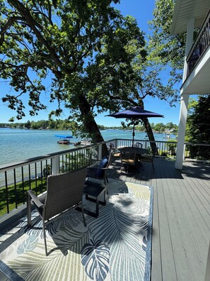Um terraço com móveis de exterior, um tapete estampado e vista para um lago com barcos.