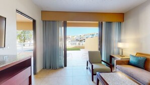 A hotel room with a balcony, a sofa, a chair, a desk, and a lamp. - Tranquil 1BR Condo at Park Royal Club Cala (Humacao)