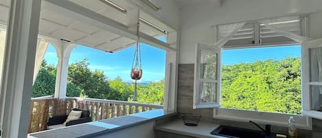 A kitchen with a view, white ceiling, and bar stools.
