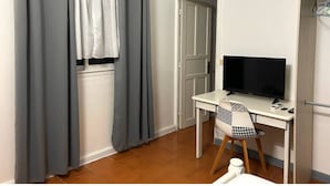Huoneessa on työpöytä, tuoli, televisio ja vaatekaappi.