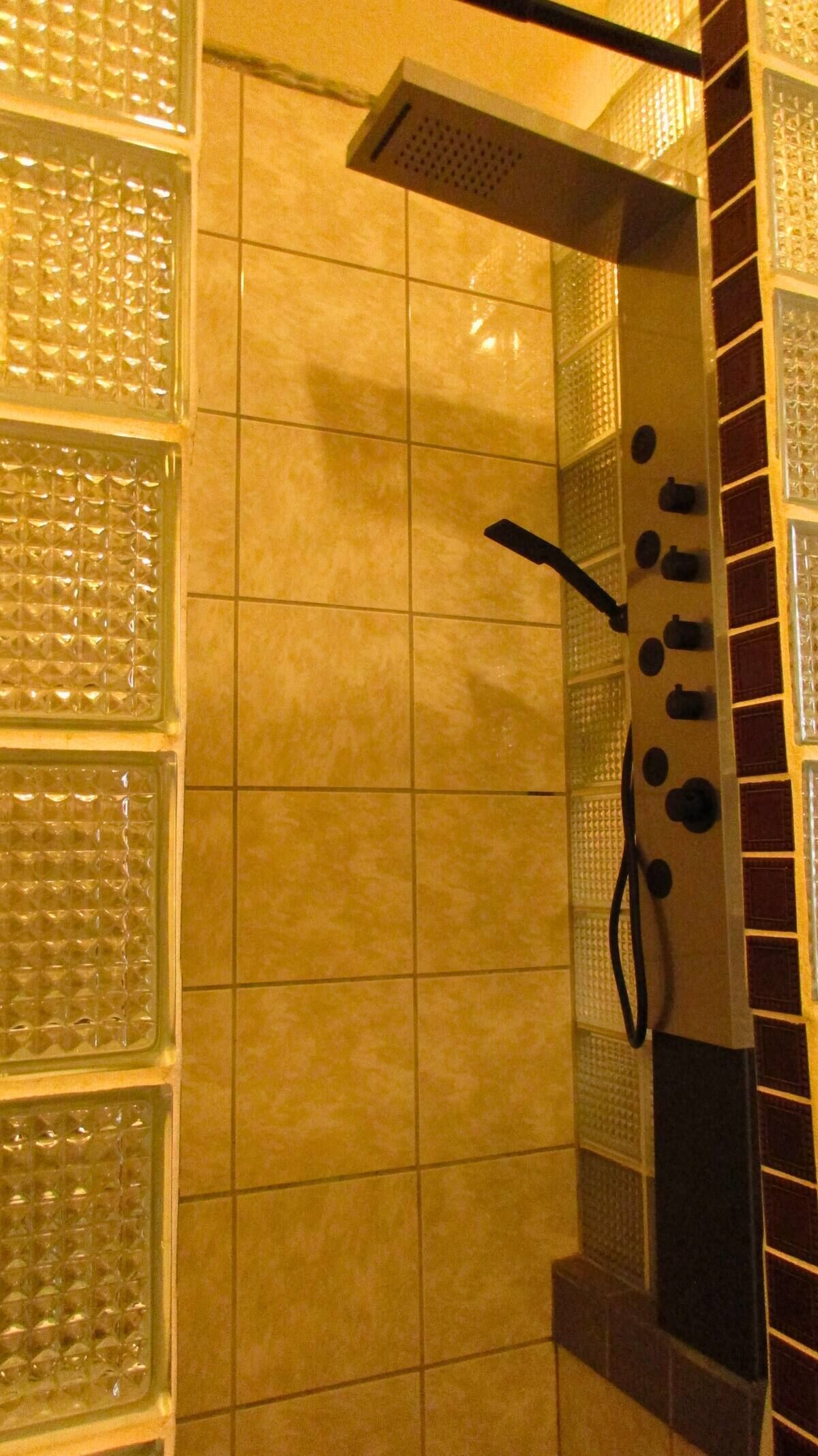 Zona de ducha con pared de azulejos y ducha con rociador negro.