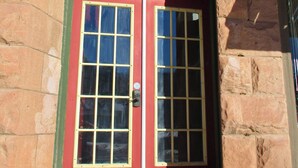 A red double door with glass panels, set in a stone building with a small step leading up to it. - The Stone room Suite #11, sleeps 5 guest (Hot Springs)