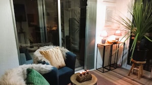 A cozy living area with a blue armchair, a small round table with candles, and a potted plant. - Appartment (2 rooms / 4 persons) with terrasse and swimminpool (Fréjus)
