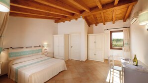 Un dormitorio con cama, armario y ventana con cortinas.