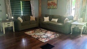 Una sala de estar con dos sofás, un tapete estampado, una mesita y una ventana con cortinas.