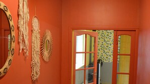 A hallway with orange walls, a mirror, and decorative wall hangings. - Gîte La Rose Trémière - Maison Avec Terrasse, Idéale Pour un Séjour en Famille (Joinville)