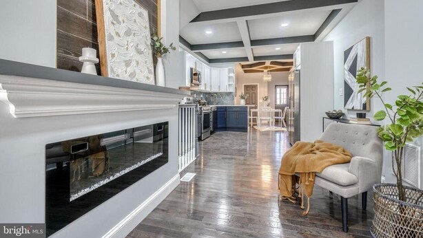Una cucina moderna con pavimento in legno scuro, mobili bianchi e un'isola centrale.