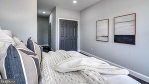 Una camera da letto con un letto grande, una porta grigia e due quadri appesi al muro.