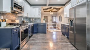 Una cucina moderna con mobili blu scuro, elettrodomestici in acciaio inossidabile e una parete di fondo in marmo.
