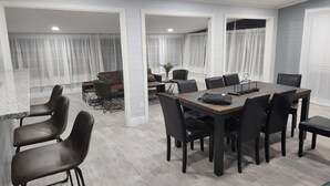 A modern dining area with a large table and chairs, a sofa, and a small side table with a plant. - Beautiful Mid Term Home in the Elegance of Winter Park!

 (Winter Park)