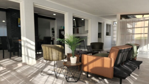 A spacious living area with a modern design, featuring a sofa, chairs, a coffee table, and a potted plant. - Beautiful Mid Term Home in the Elegance of Winter Park!

 (Winter Park)