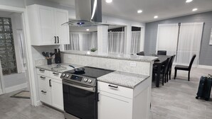 A modern kitchen with white cabinets, a stainless steel range hood, and a built-in oven. - Beautiful Mid Term Home in the Elegance of Winter Park!

 (Winter Park)