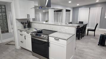 A modern kitchen with white cabinets, a stainless steel range hood, and a built-in oven.