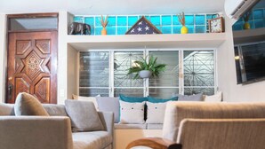 Una sala de estar con un sofá, una puerta de madera y un ventanal con vidrieras decorativas.