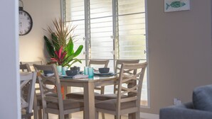 Un comedor con una mesa redonda, cuatro sillas, una planta en maceta y un reloj en la pared.
