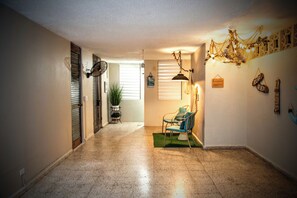 A hallway with a potted plant, a chair, and a hanging light fixture.