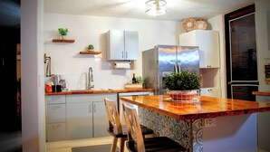 Una cocina moderna con armarios blancos, encimera de madera y una isla integrada con sillas.