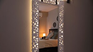 Un dormitorio con una cama, una mesita de noche, una lámpara y un reloj de pared.