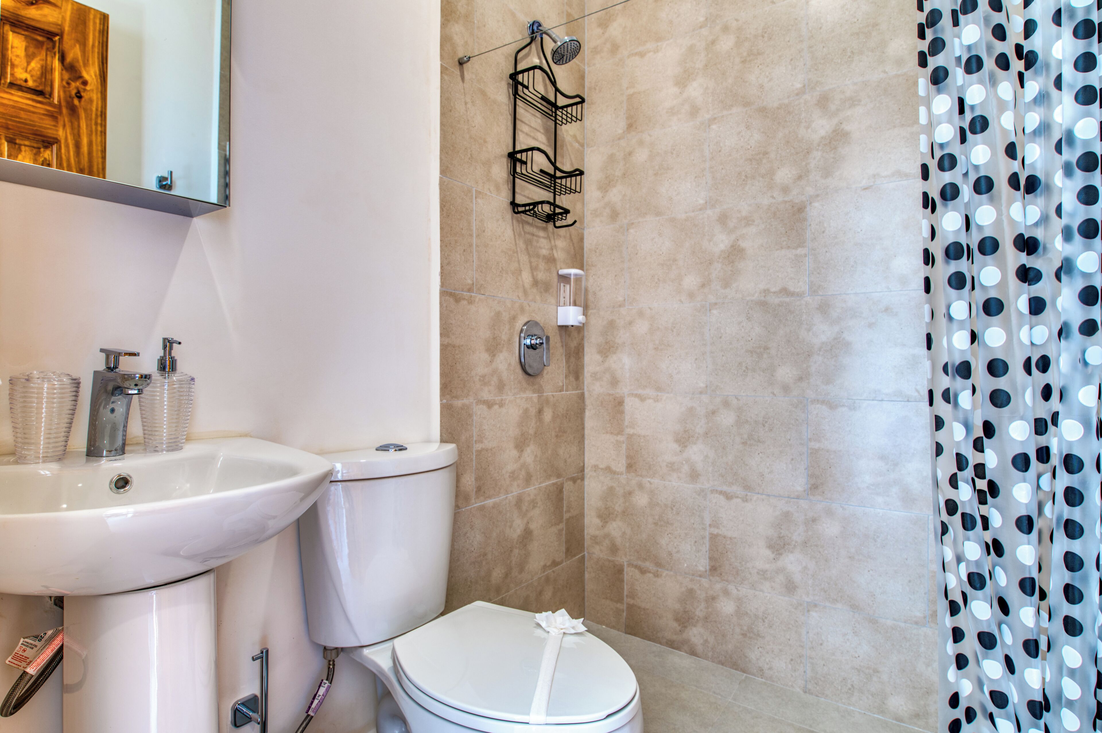 Un bagno con lavandino, WC e doccia, tutti in bianco.