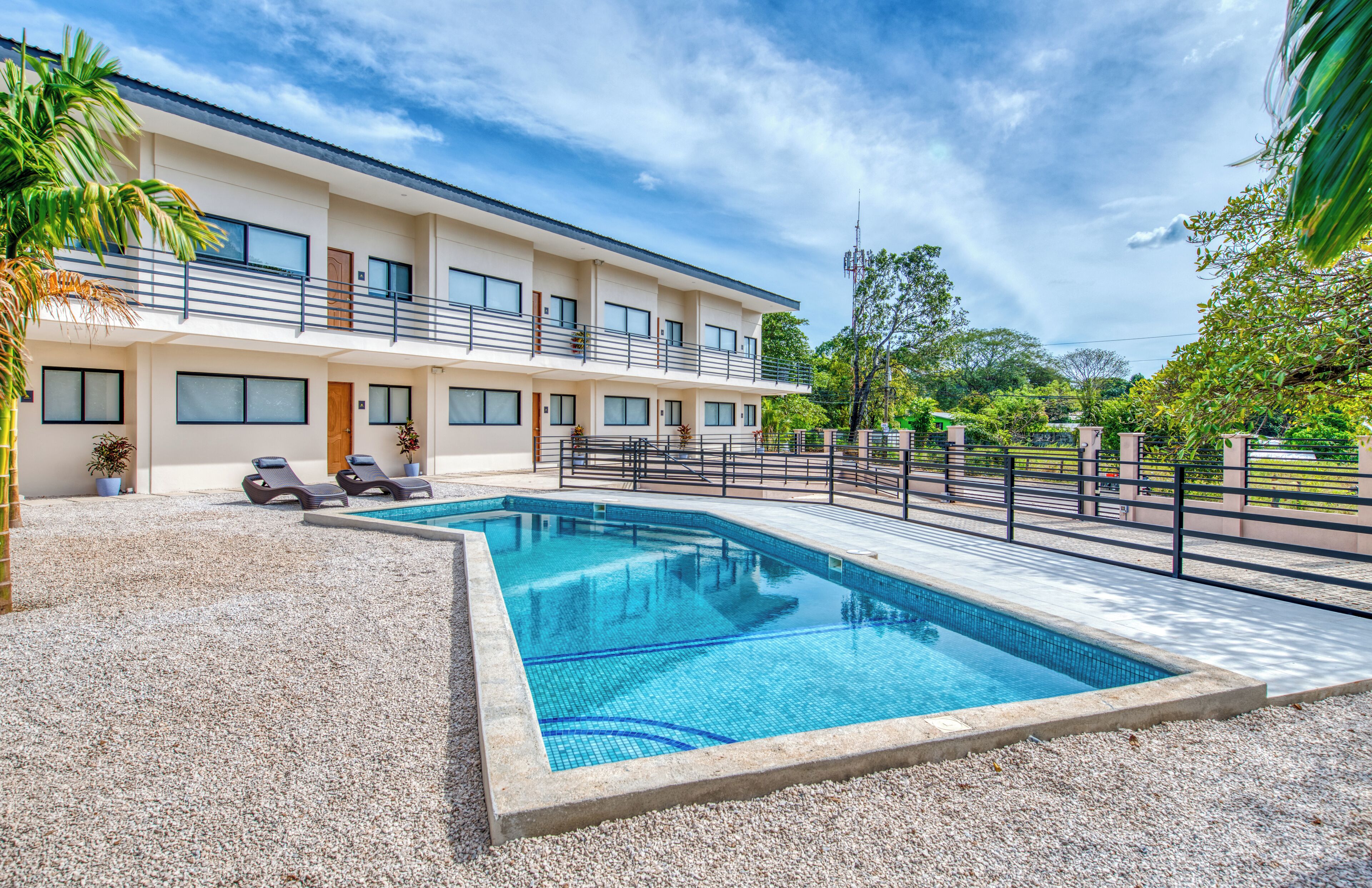 A modern hotel with a swimming pool, multiple balconies, and a well-maintained garden area.
