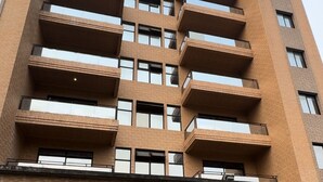 Ein mehrgeschossiges Wohngebäude mit Ziegelaußenwand, Balkonen in jeder Etage und einem zentralen Eingang mit einer verzierten Tür.