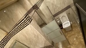 Ein Badezimmer mit Marmorboden, einem weißen Waschbecken und einem Spiegel mit dekorativem Rahmen.