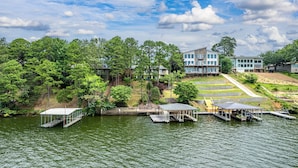 A lakeside property with a dock, a covered pavilion, and a building with multiple windows and balconies. - Beautiful, Private Lake House with Double Dock (Hot Springs)