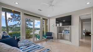 A bedroom with a bed, a chair, a TV, and a view of the outdoors. - Beautiful, Private Lake House with Double Dock (Hot Springs)