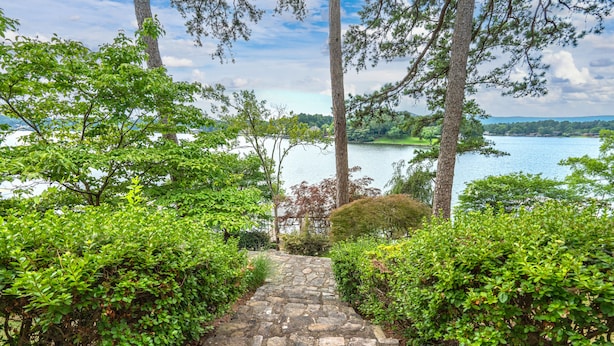 A stone pathway leading to a lake surrounded by dense greenery and trees. - Beautiful, Private Lake House with Double Dock (Hot Springs)