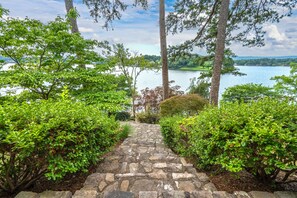 A stone pathway leading to a lake surrounded by dense greenery and trees. - Beautiful, Private Lake House with Double Dock (Hot Springs)