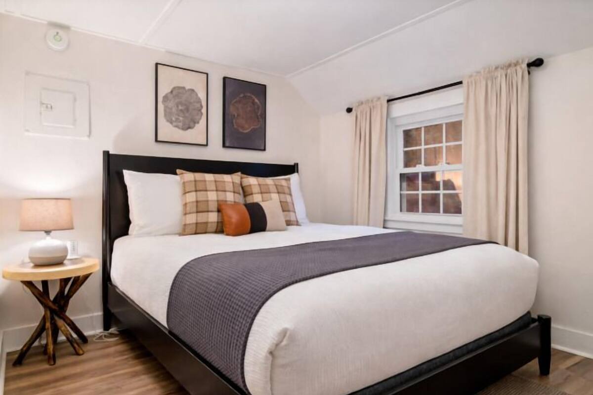 A neatly arranged bedroom with a bed, bedside table, and a window with curtains.