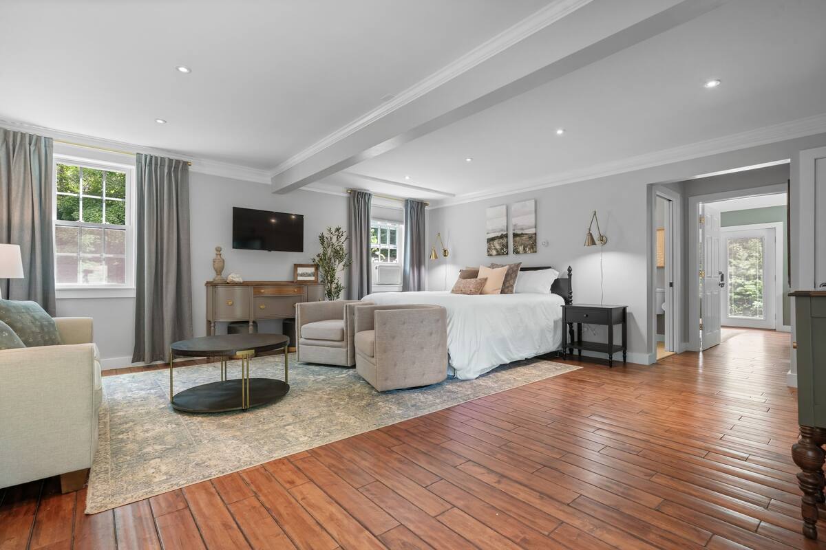 A spacious bedroom with a large bed, a desk, a chair, and a television.