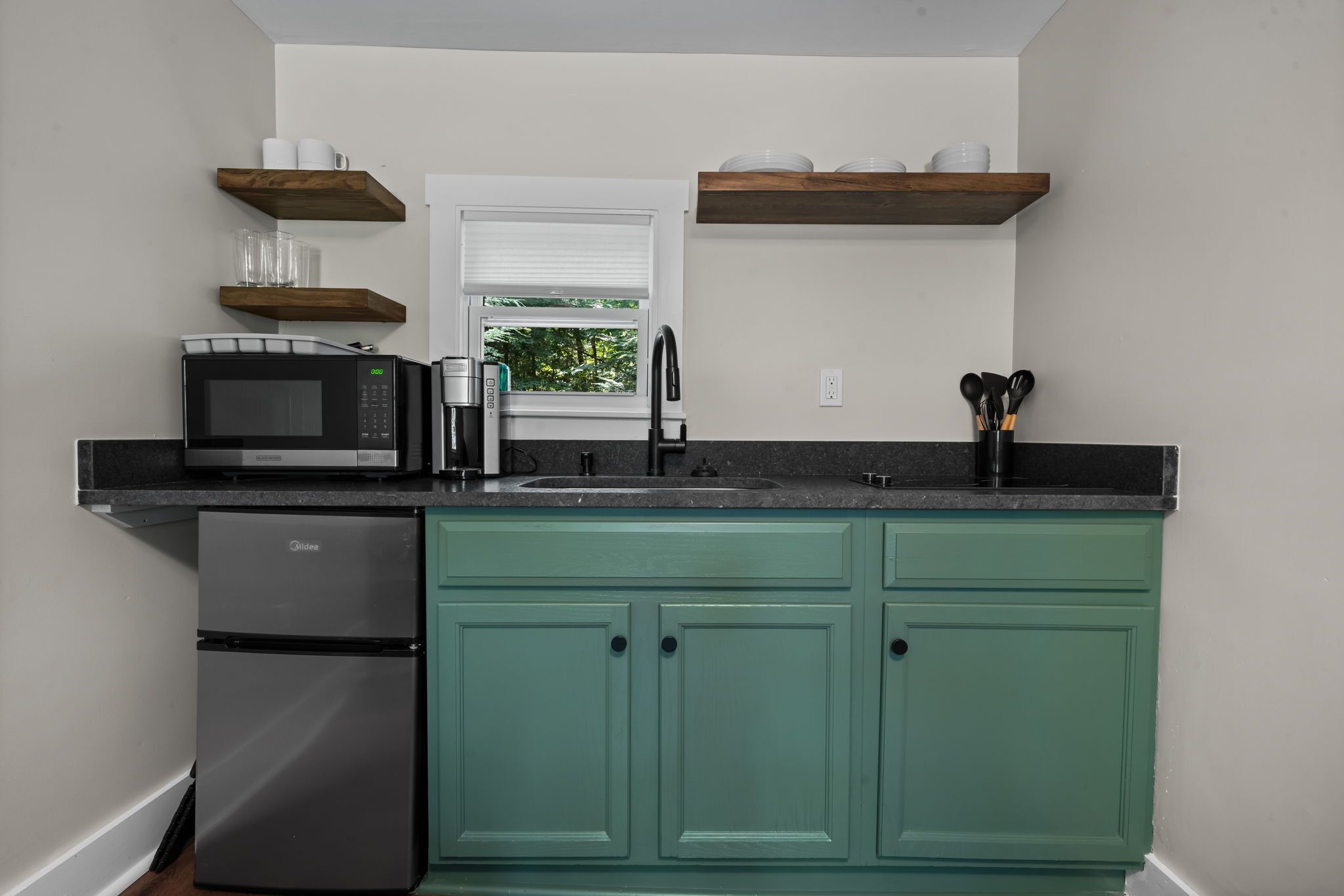 A compact kitchen with teal cabinets, a built-in microwave, and a refrigerator.