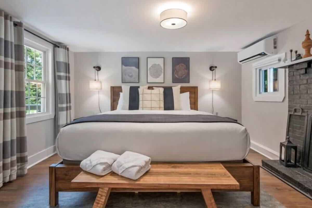 A neatly made bed with a headboard, bedside lamps, and a small wooden table with towels.