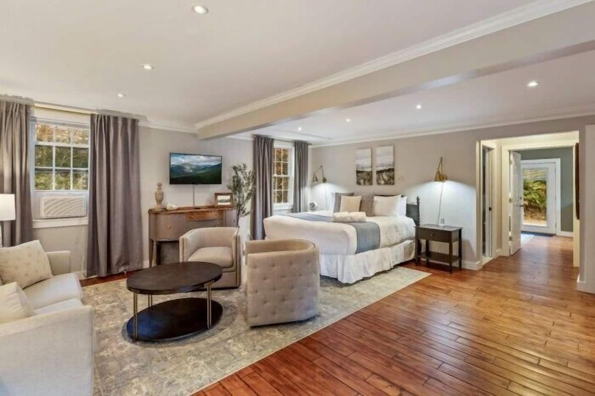 A spacious living room with a large bed, a sofa, a coffee table, and a TV.